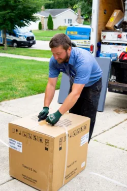 TR Miller technician loading a high-efficiency residential furnace onto a branded service truck for a heating installation in Elgin, IL.