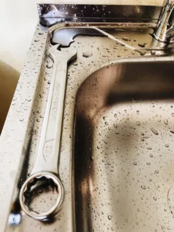 stainless steel wrench sitting on the edge of a residential sink