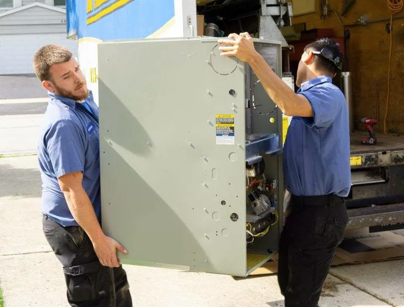 Two TR Miller technicians removing an old AC unit from a residential property