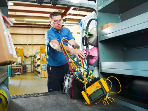 TR Miller HVAC Service Manager Ryan Laske loading professional diagnostic and cooling equipment into a service truck for a residential air conditioning installation.