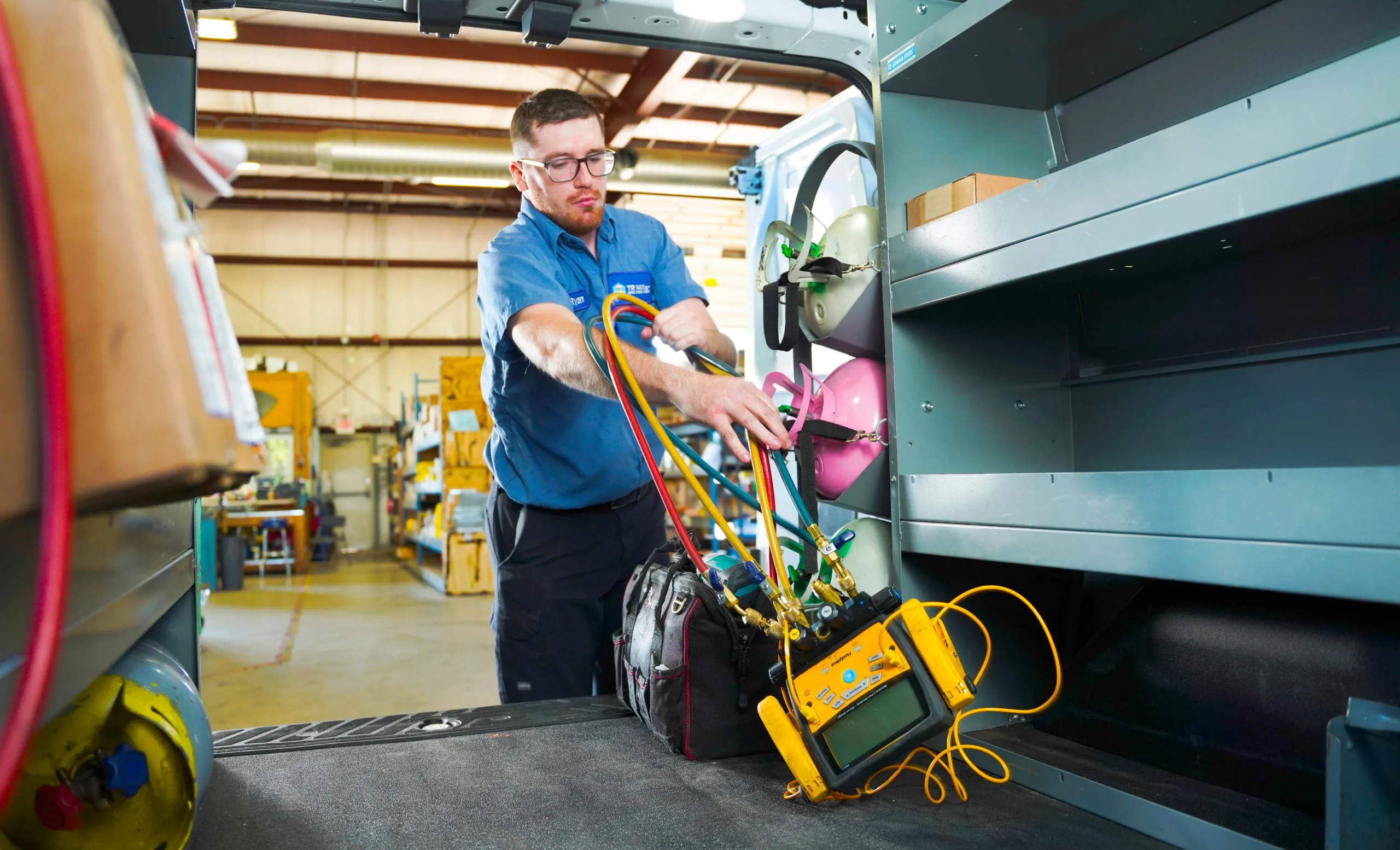 TR Miller HVAC Service Manager Ryan Laske loading professional diagnostic and cooling equipment into a service truck for a residential air conditioning installation.