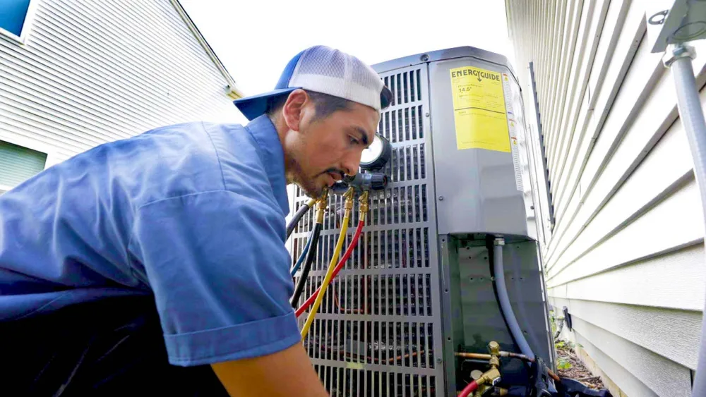 tr miller hvac technician inspecting an air conditioner in the chicago suburbs
